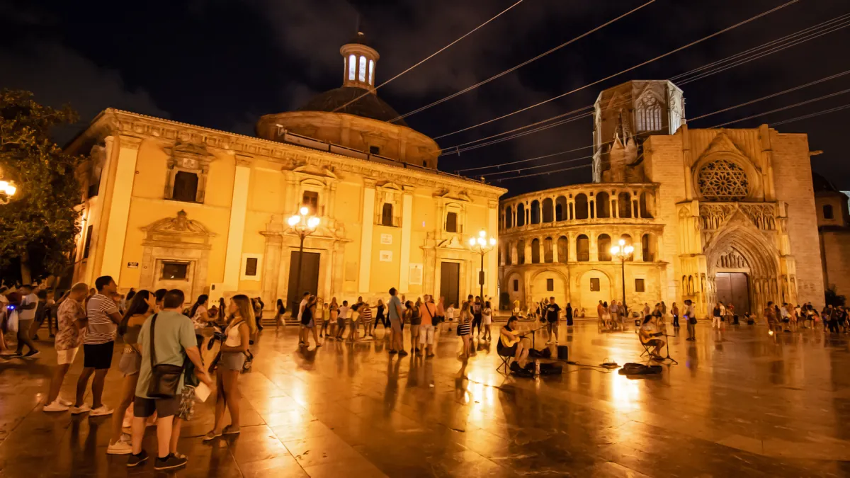 Plaza de la Virgen in Valencia at night, with the lit cathedral door and the square's fountain