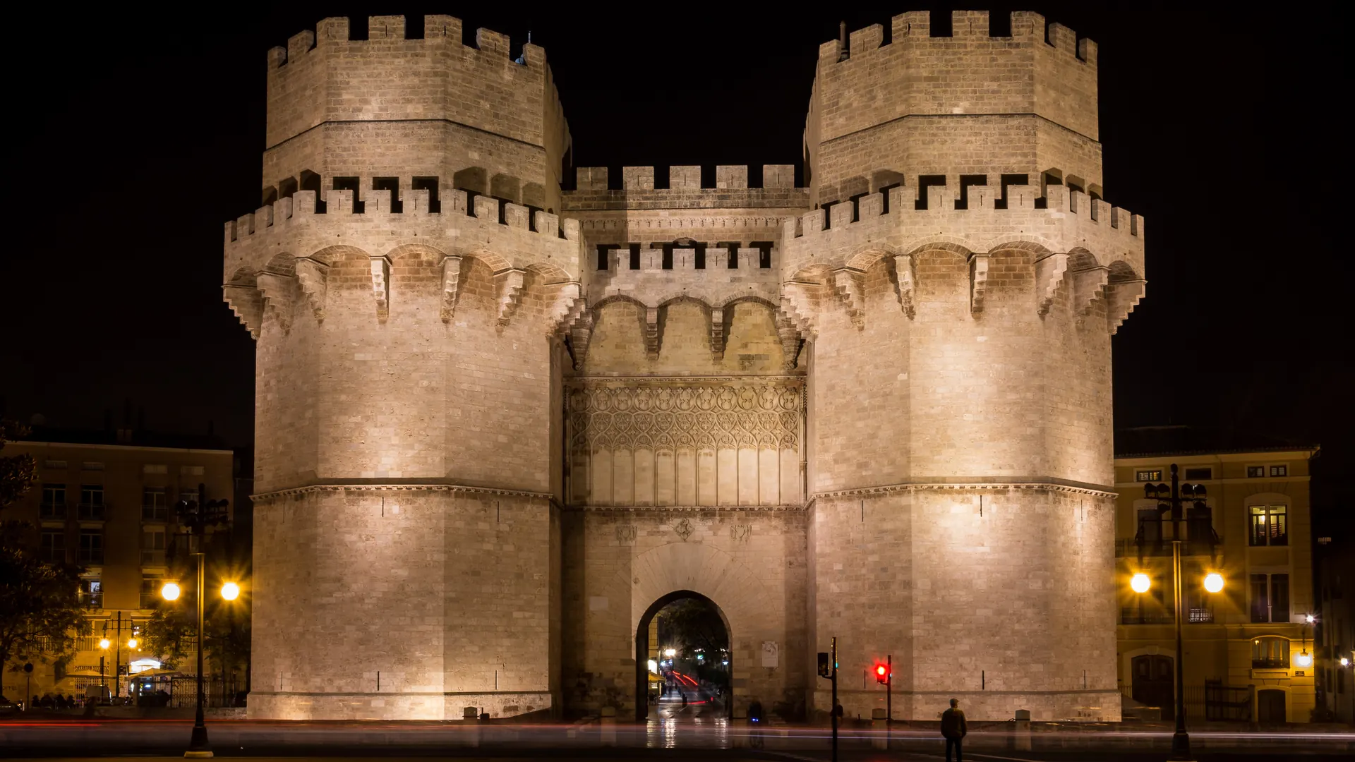 The two crenellated towers of the Torres de Serranos in Valencia, floodlit in warm stone against a black night sky